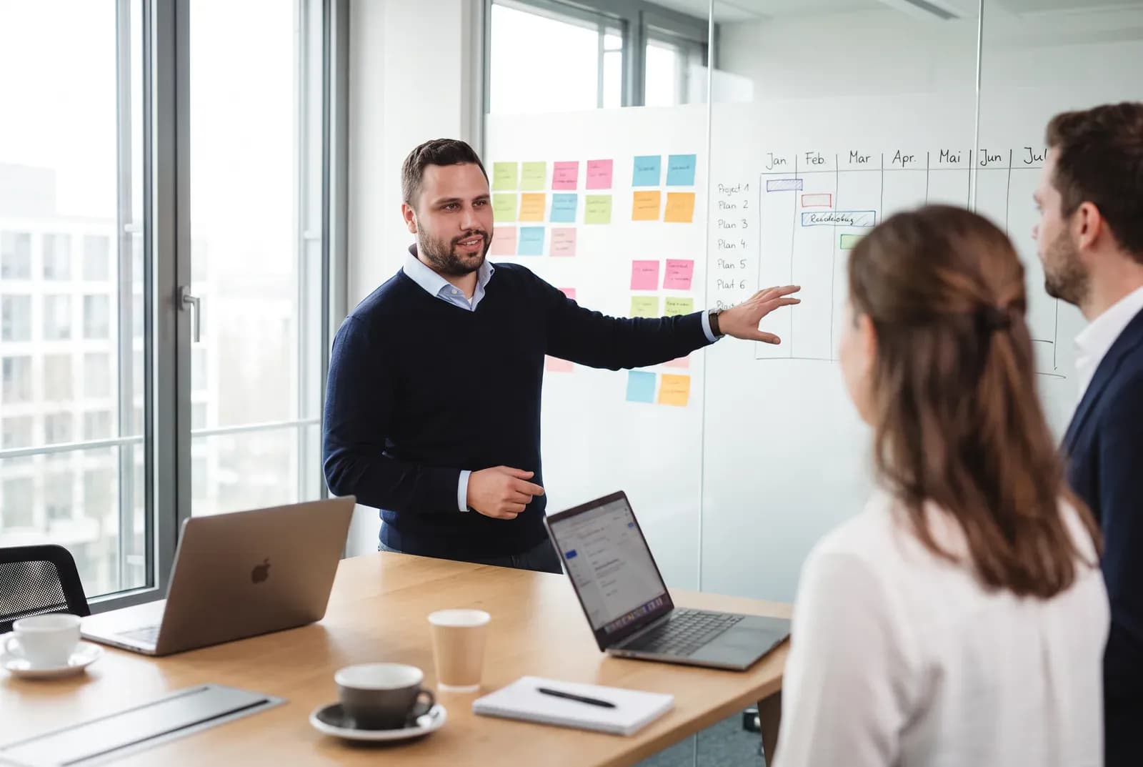 Kai Seegers erklärt im Besprechungsraum ein Scrum-Board mit Haftnotizen